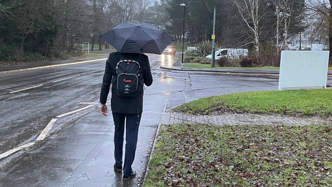 Commuter walking in the rain wearing a Futliit LED backpack