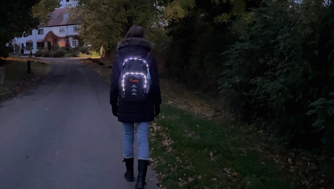 A teen wearing a Futliit LED backpack walking in a dark street