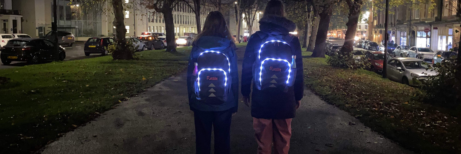 Two teens wearing Futliit LED backpacks at night