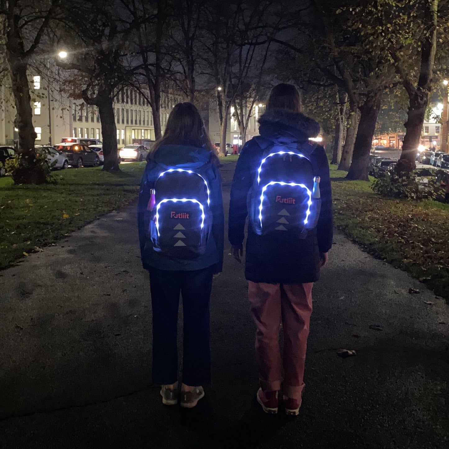 Two teens wearing Futliit LED backpacks at night